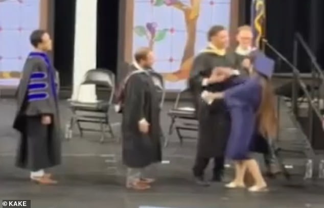 Kansas high school administrator forcibly shakes hands with celebrating graduates